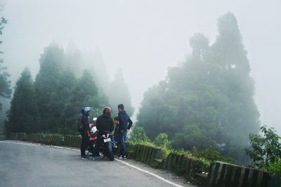 Rear view of people riding motorcycle on road