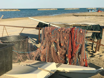 Fishing net on beach by sea against sky