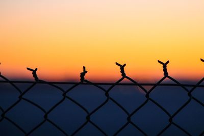 Barbed wire against clear sky during sunset