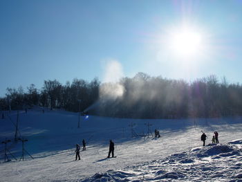 People on snowy field against sky during winter