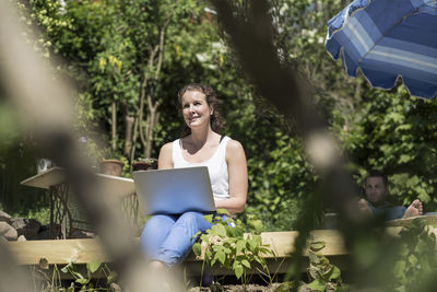 Smiling mid adult woman with laptop sitting on terrace