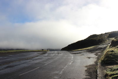 Empty road against cloudy sky during foggy weather