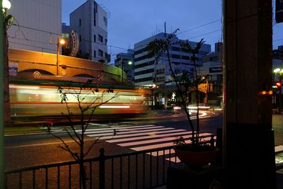 Illuminated city street against sky at dusk