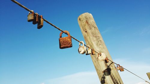 Low angle view of rusty padlocks on metallic fence against sky