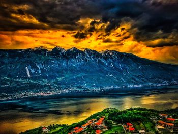 Scenic view of lake and mountains against orange sky