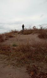 Man walking on field against sky