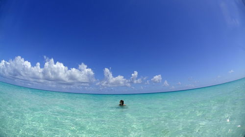 Fish-eye lens view of woman in sea against blue sky at beach