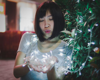 Young woman looking down while standing against plants