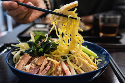 Close-up of person holding noodle in plate