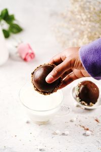 Cropped hand of person holding seashell on table