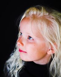 Close-up portrait of cute baby girl over black background