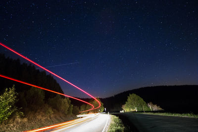 Light trails on road against clear sky at night