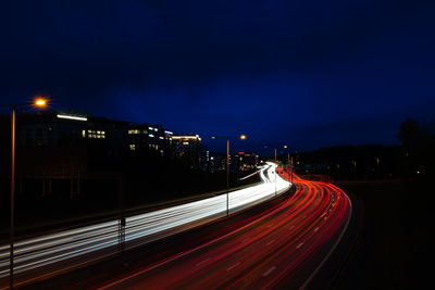 Light trails on road against sky at night