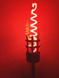Close-up of illuminated lamp against red background