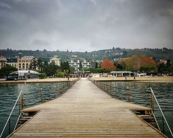 Pier over river in city against sky