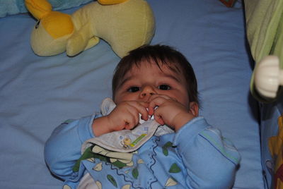 Portrait of cute baby boy sucking pacifier in crib at home