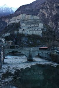 Arch bridge over river against buildings