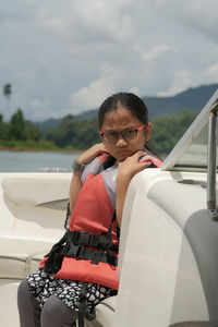 Cute girl wearing life jacket sitting on boat