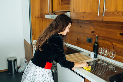 Side view of girl cleaning kitchen at home