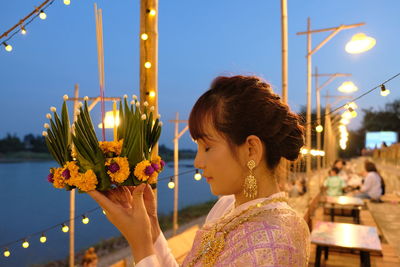 Portrait of woman with flowers against sky