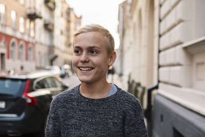 Happy teenage boy looking away at roadside during weekend