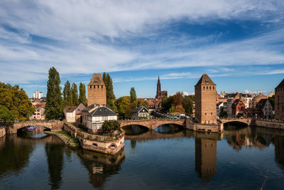 Bridge over river by buildings against sky