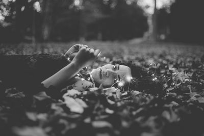 Portrait of young woman lying on field at park during autumn