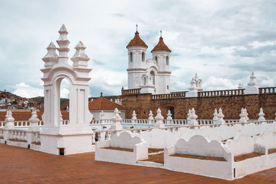 Church amidst buildings against cloudy sky in city