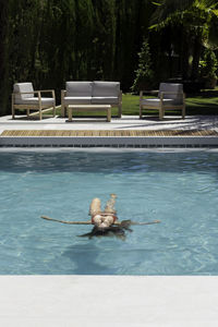 Vertical view of young woman in bikini relaxing upside down floating in the middle of the pool