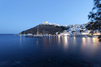 Scenic view of sea by buildings against clear blue sky