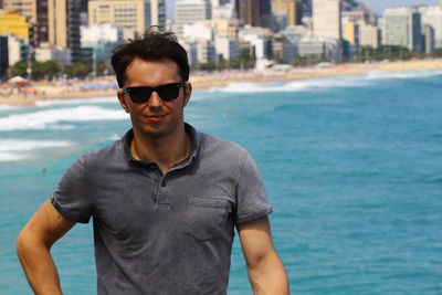 Portrait of young man wearing sunglasses against sea