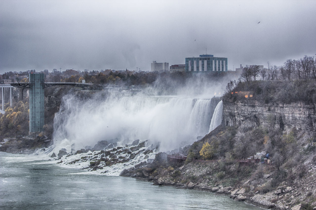 WAVES SPLASHING ON DAM AGAINST SKY