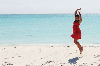 Full length portrait of smiling young woman standing on beach