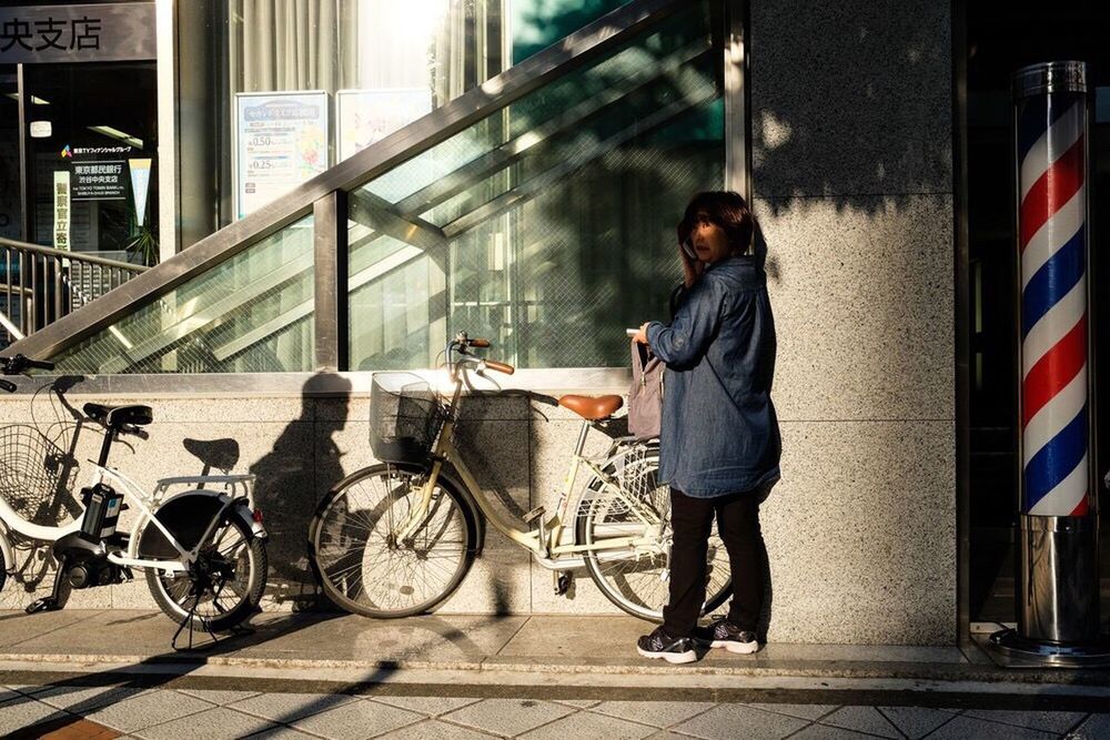 full length, bicycle, one person, young adult, transportation, casual clothing, built structure, architecture, real people, side view, standing, building exterior, outdoors, lifestyles, day, young women, city, adult, people, adults only