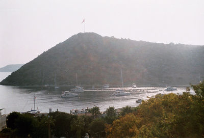 Boats sailing in sea by mountains against sky