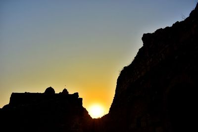 Low angle view of silhouette cliff against sky