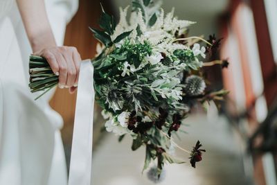 Midsection of woman holding white flower