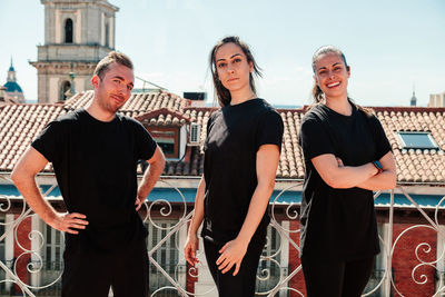 Portrait of young men standing against railing in city