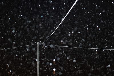 Low angle view of snowflakes on shore against sky at night