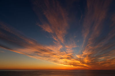 Scenic view of sea against dramatic sky during sunset