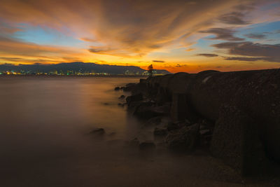 Scenic view of sea against cloudy sky during sunset