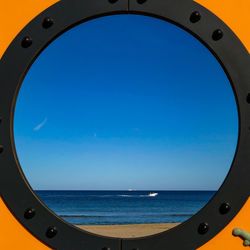 Scenic view of sea against clear blue sky seen through window