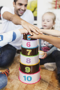 Cropped image of teacher and students piling up hands on number blocks