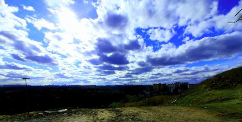 Panoramic shot of road amidst field against sky