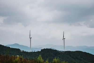 Scenic view of industrial windmills against cloudy sky
