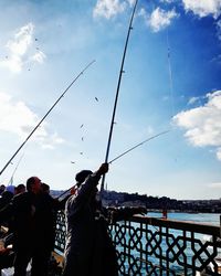 People standing by railing against sky