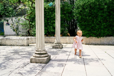 Girl standing by plants against trees