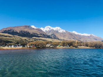 Scenic view of sea and mountains against clear blue sky