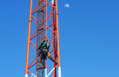 Low angle view of crane against clear blue sky