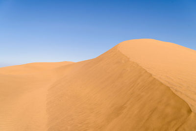 Scenic view of desert against clear blue sky